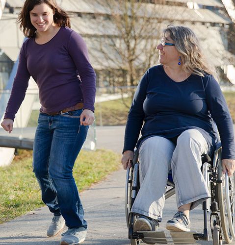 Zwei Frauen auf einem Spaziergang, eine davon im Rollstuhl