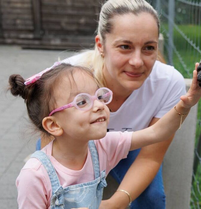 [Translate to Italienisch:] Sayra füttert eine Ziege}