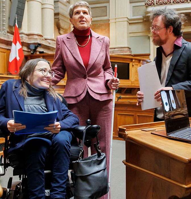 Quatre personnes en situation de handicap dans la salle du Conseil national du Palais fédéral à Berne
