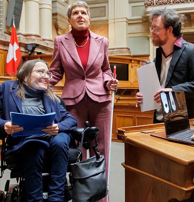 Quattro persone con disabilità nella sala del Consiglio nazionale del Parlamento federale a Berna