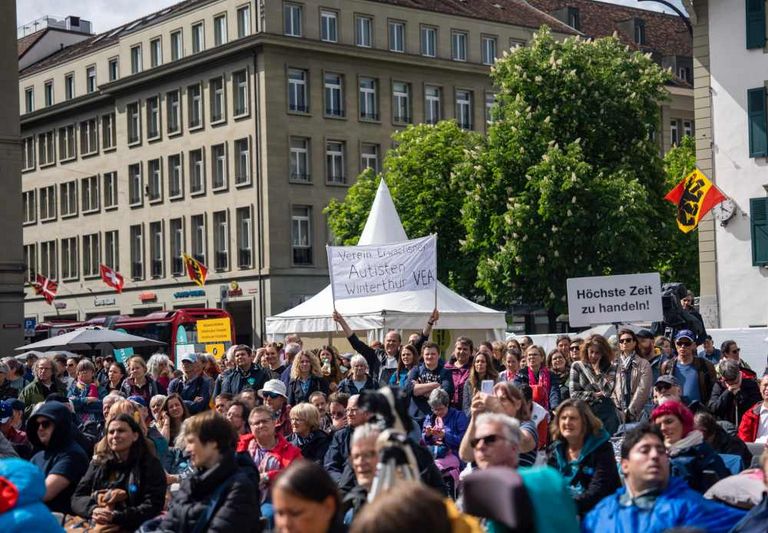 Pubblico con manifesti sulla piazza federale di Berna