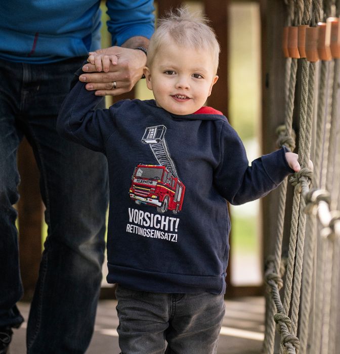Un garçon traverse un pont en tenant la main d'une personne en arrière-plan