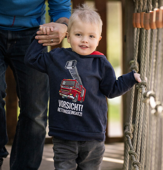 Bambino attraversa un ponte tenendo la mano di una persona sullo sfondo