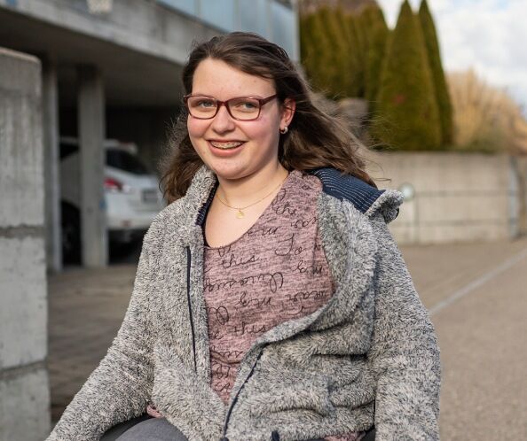 Junge Frau draussen in ihrem Rollstuhl