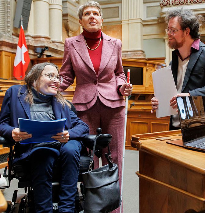 Trois personnes handicapées dans la salle du Conseil national du Palais fédéral