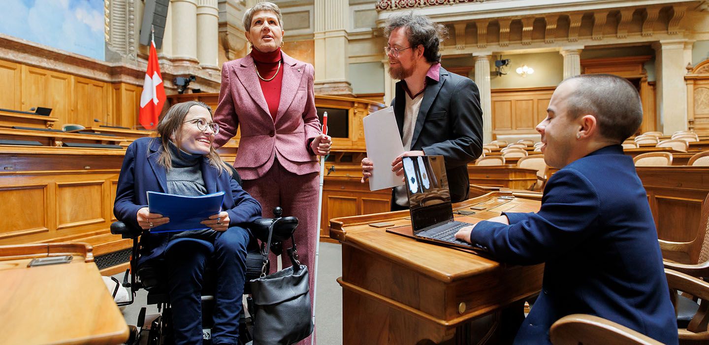 Quattro persone con disabilità nella sala del Consiglio nazionale del Parlamento federale a Berna