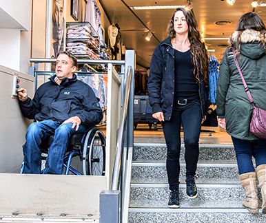 Rollstuhlfahrer im Treppenlift eines Einkaufszentrums