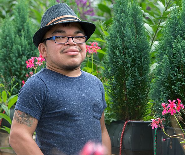 Jeune homme portant un chapeau dans un jardin