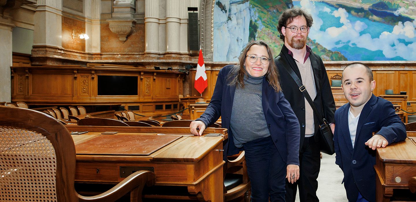 Drei Menschen mit Behinderungen im Nationalratssaal des Schweizer Parlaments