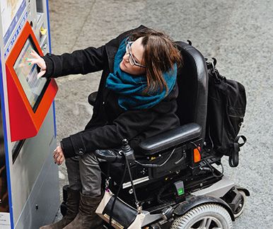 Donna in sedia a rotelle al distributore di biglietti
