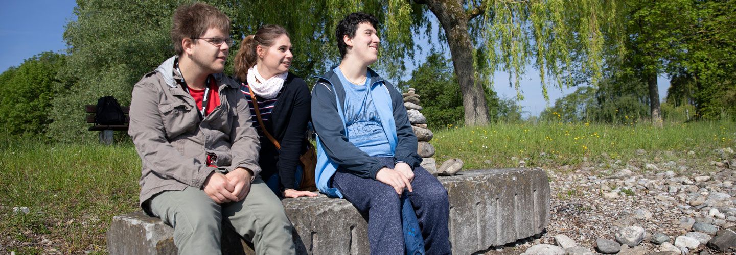 Drei junge Menschen sitzen draussen