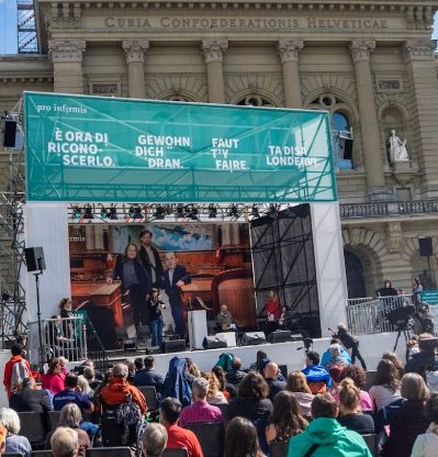 Des centaines de personnes devant une scène lors d'un événement de Pro Infirmis sur la Place fédérale