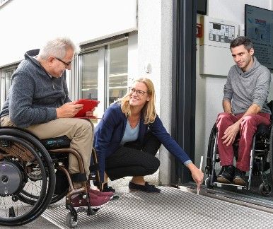 Des hommes en fauteuil roulant mesurent un bâtiment
