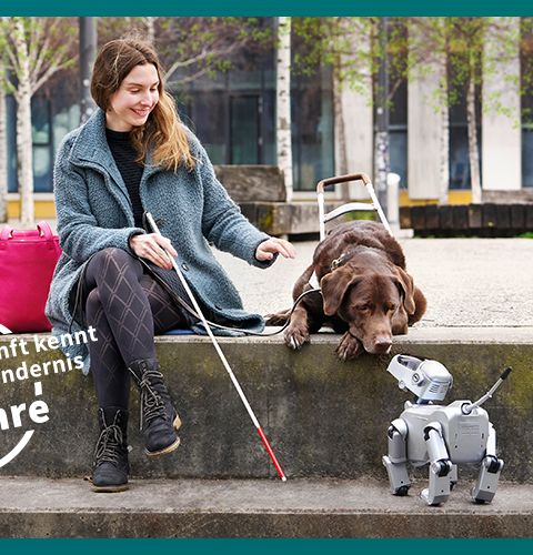Frau sitzt in einem Park, ihr Blindenhund beschnuppert einen kleinen Roboter-Hund