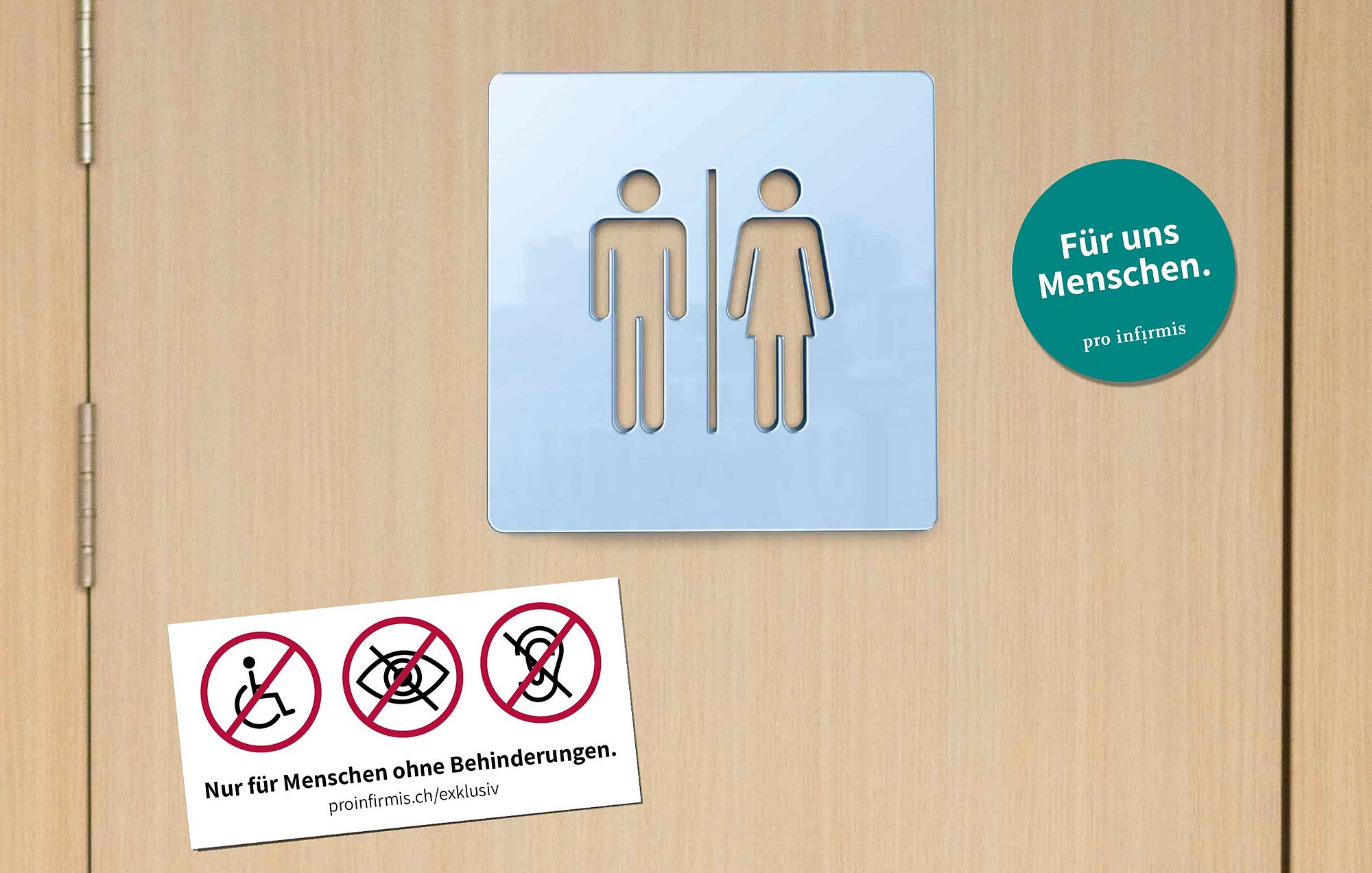 Eine Toilettentür mit dem Symbol für Mann und Frau. Beispielhaft ist links unten der Kleber mit der Aufschrift «Nur für Menschen ohne Behinderungen» angeklebt. Rechts oben der Sticker mit der Botschaft «Für uns Menschen».