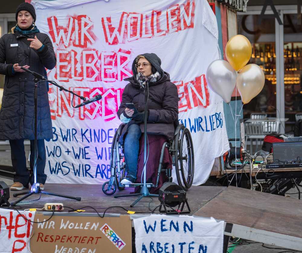 Person im Rollstuhl hält eine Rede bei einer Kundgebung am Helvetiaplatz