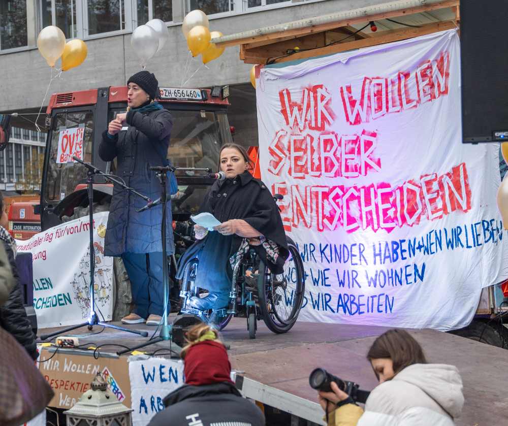Frau im Rollstuhl bei einer Rede auf der Bühne am Helvetiaplatz