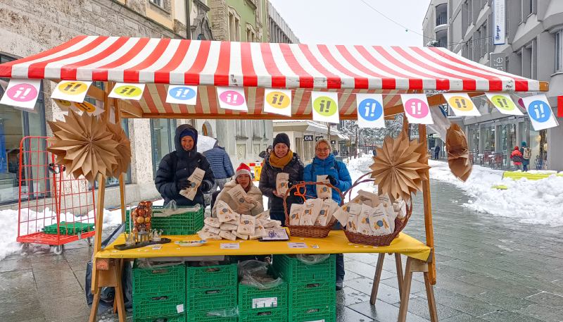 Mehrere Personen stehen hinter einem Stand mit inklusiven Grittibänzen auf dem Weihnachtsmarkt in Chur.