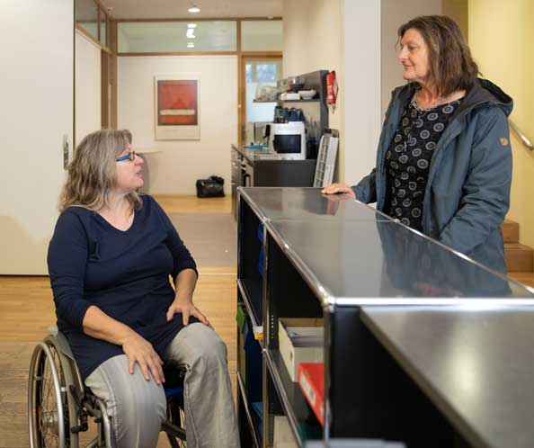 [Translate to Italienisch:] Susanna Lüthi im Rollstuhl berät eine Klientin