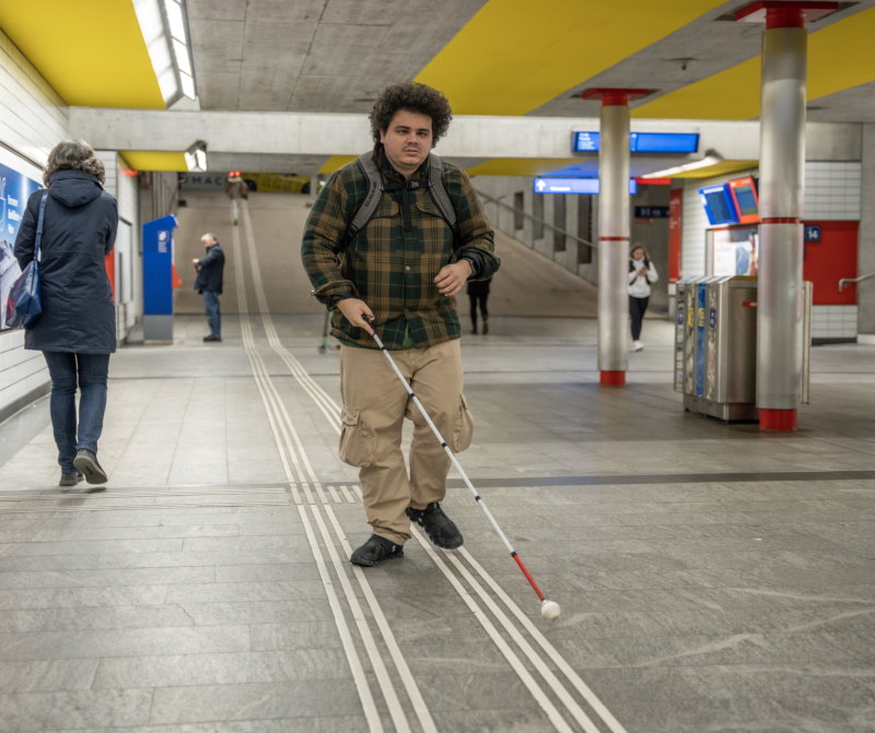 Un uomo con una disabilità visiva cammina in una stazione