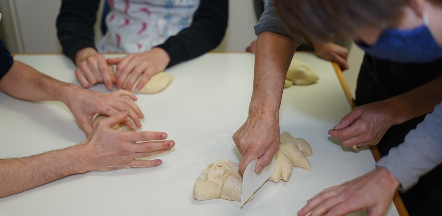 Plusieurs personnes confectionnent des bonshommes en pâte à la même table.