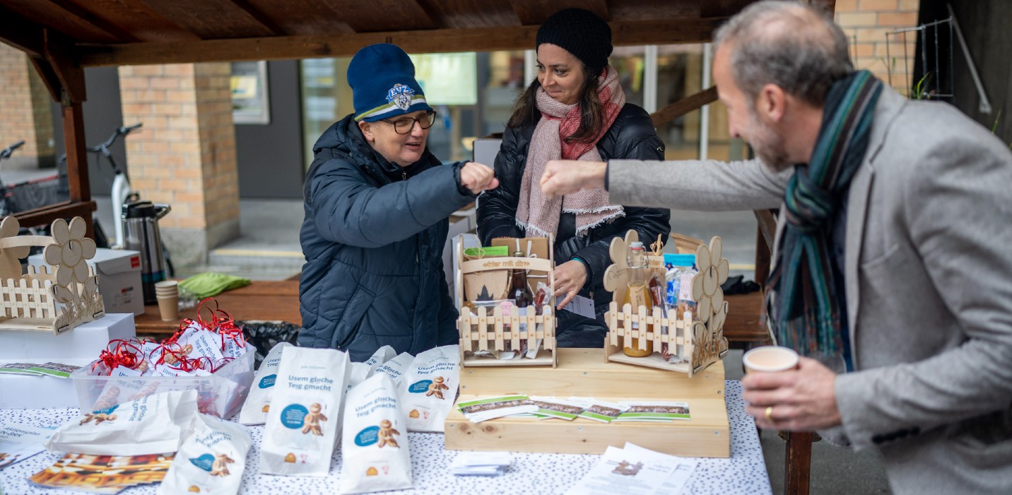 Un stand avec des bonshommes de St-Nicolas ; deux personnes se saluent.