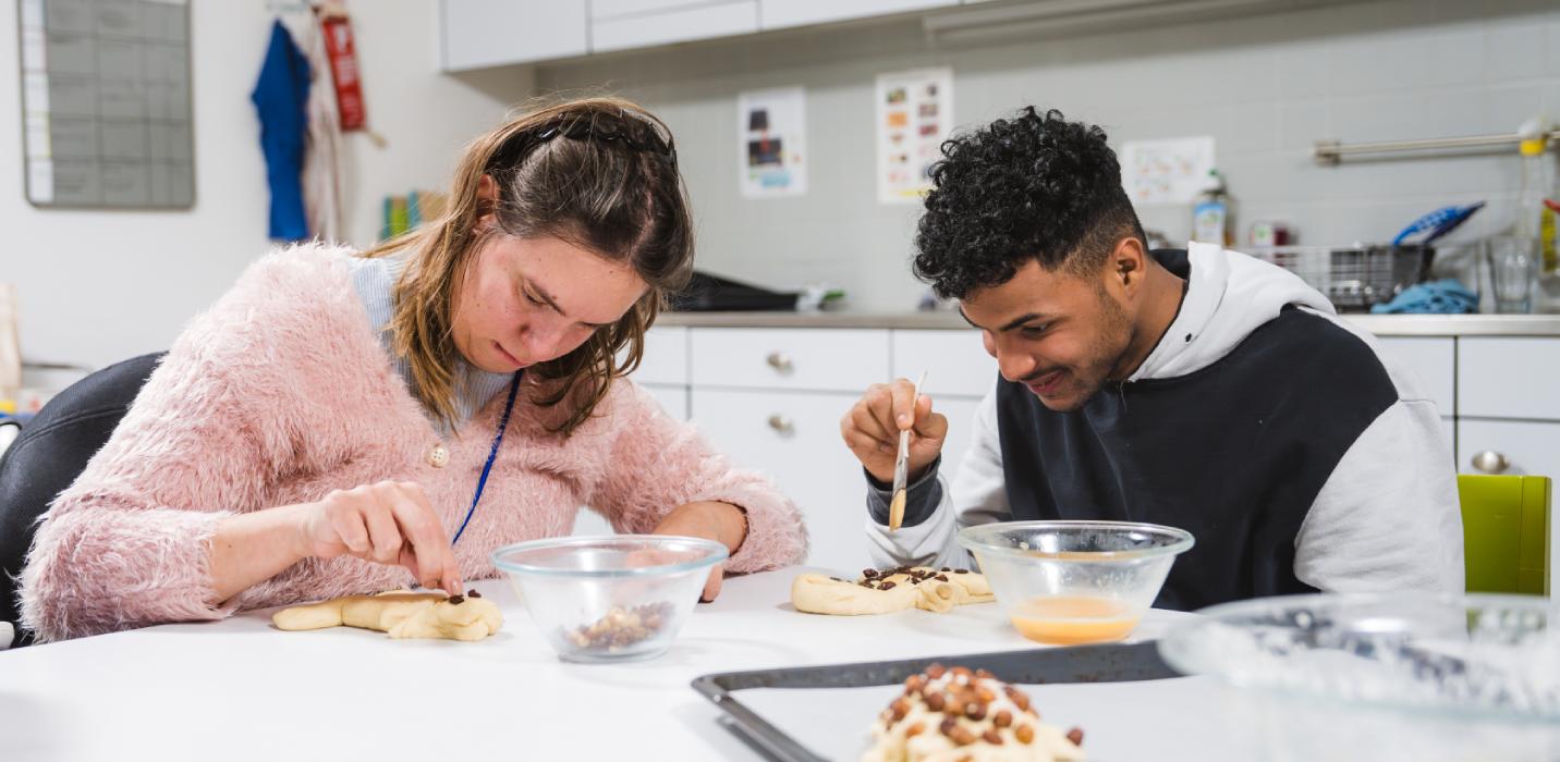 Deux jeunes gens confectionnent des bonshommes de St-Nicolas dans la cuisine de l'école d'autonomie