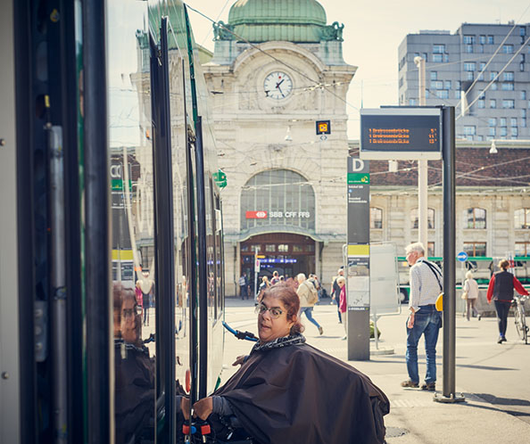 Eine Frau im Elektrorollstuhl steigt selbstständig in ein Tram ein. 