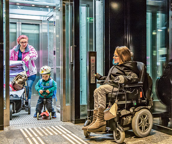 Rollstuhlfahrerin, Frau mit Kinderwagen und Kind mit Roller an Lift