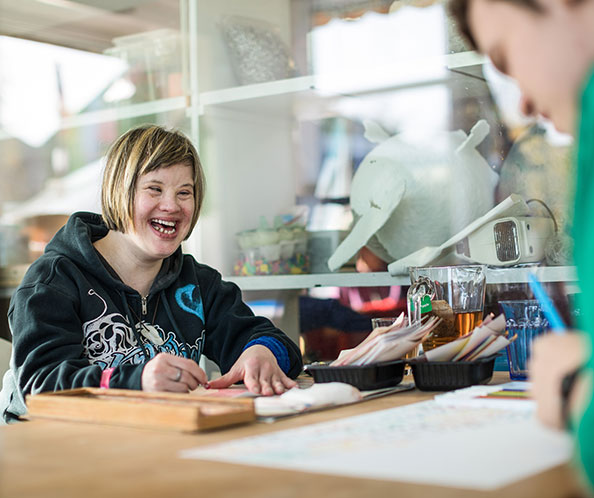femme avec le syndrome de Down riant pendant qu’elle dessine