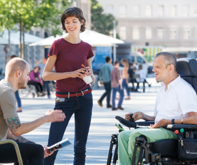 [Translate to Französisch:] Ein Mann im Rollstuhl diskutiert mit zwei weiteren Menschen